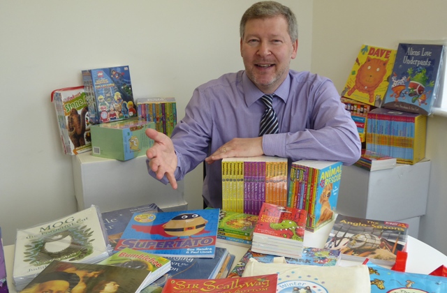 Simon Dolby, chief executive of the KM Charity Team, with the books to be won by a school joining the charity’s reading reward scheme Buster’s Book Club.